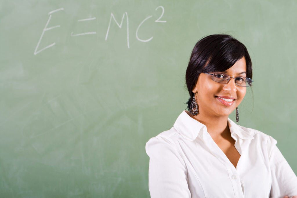 woman professor standing smiling in front of a chalkboard