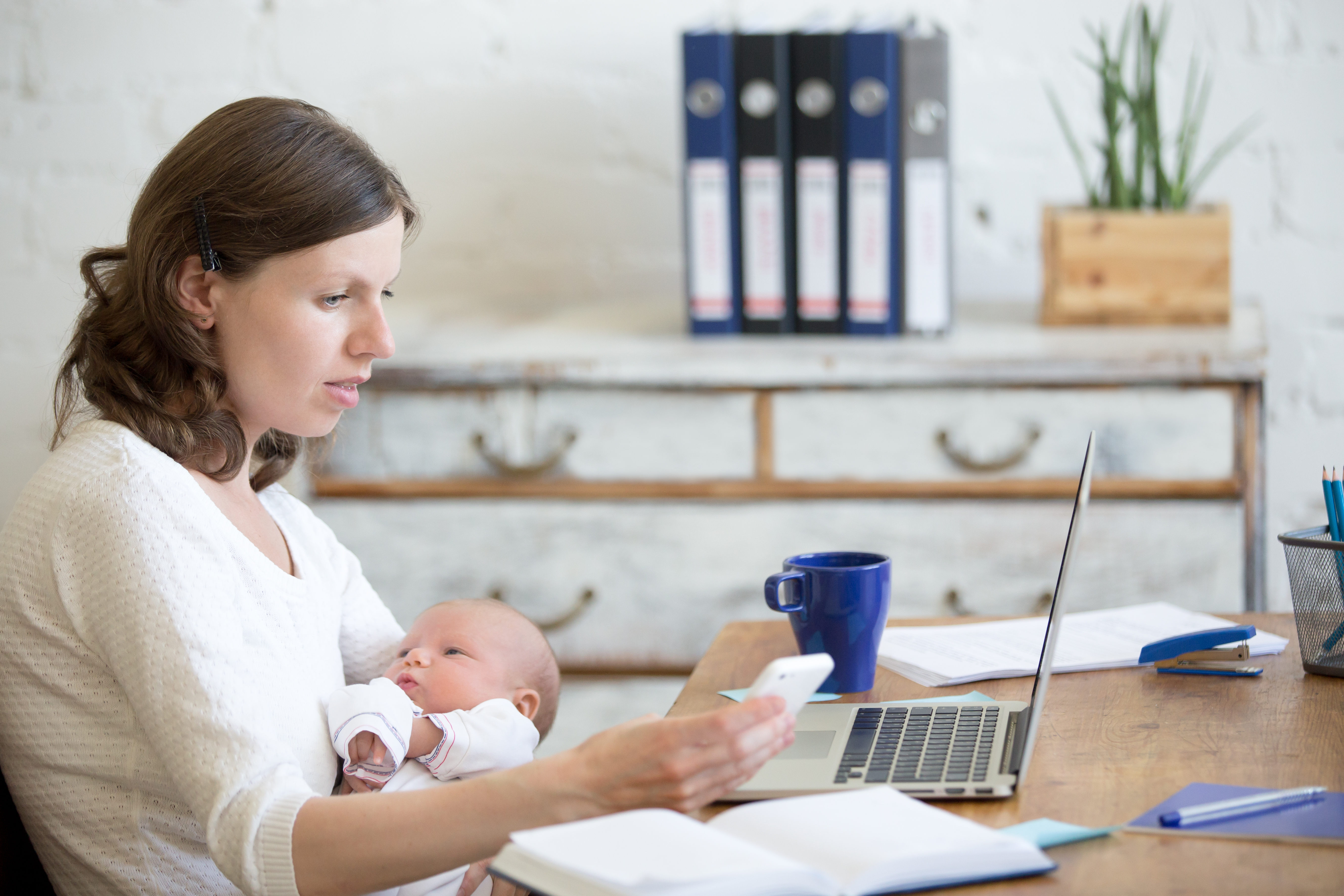 mom working at a desk holding a baby