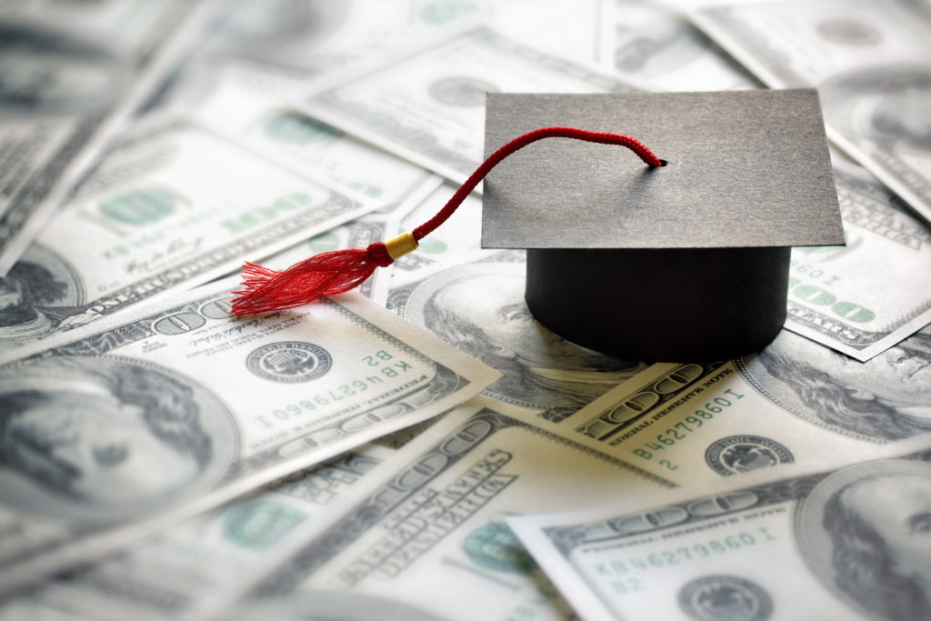 graduation cap sitting on top of hundred dollar bills