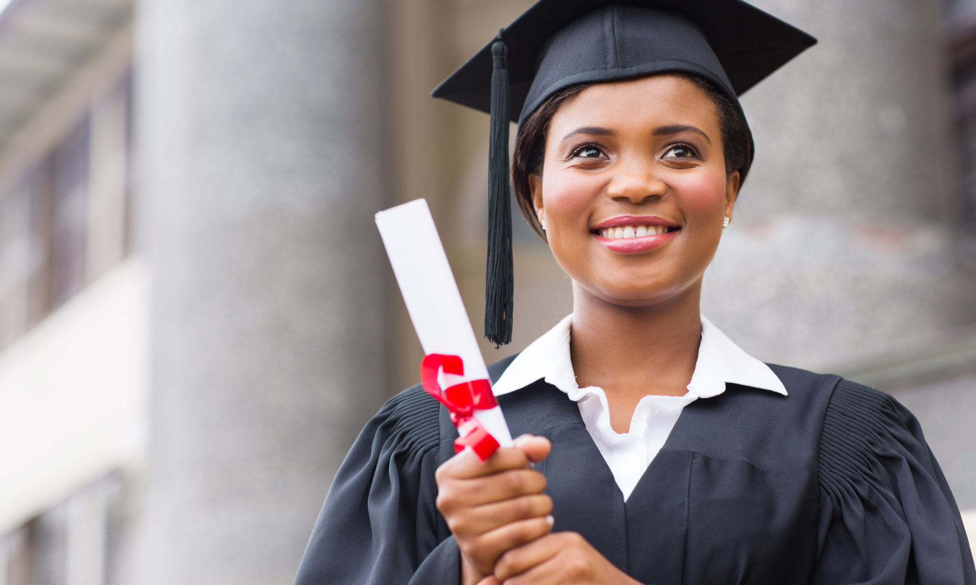 African American woman smiling wearing cap and gown and holding diploma